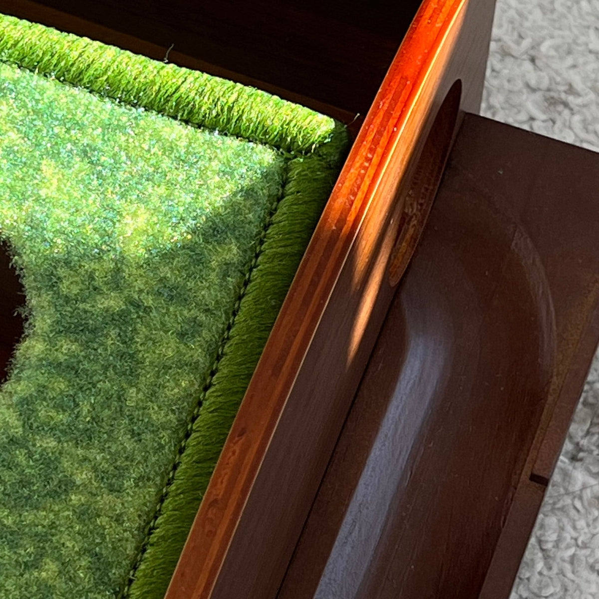Tapis de putting Greenwood avec bois de chene, avec les détails du rail de retour aimanté et deux trous de différent diametre pour la précision